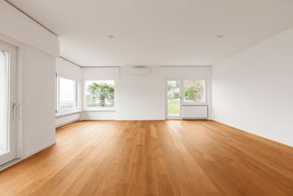 Großer, lichtdurchfluteter Raum, in welchem Parkett verlegt ist.